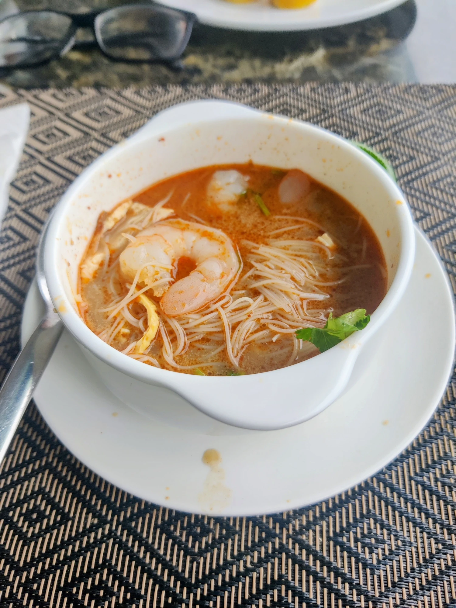 A steaming bowl of authentic Sarawak Laksa with fresh prawns, vermicelli noodles, and aromatic spice broth