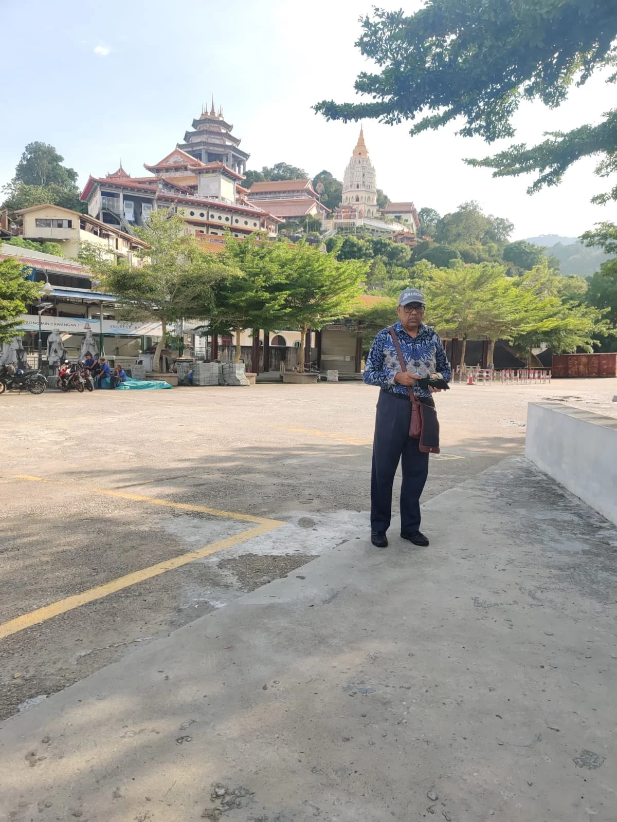Male traveler standing in the vast courtyard of Kek Lok Si Temple with the Pagoda of Ten Thousand Buddhas in the background