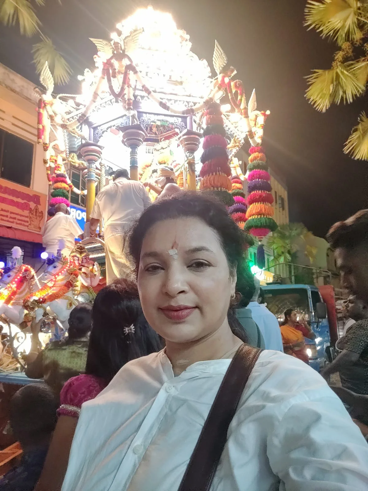 Female traveler selfie right in front of the illuminated Rath procession in Little India, Penang at night