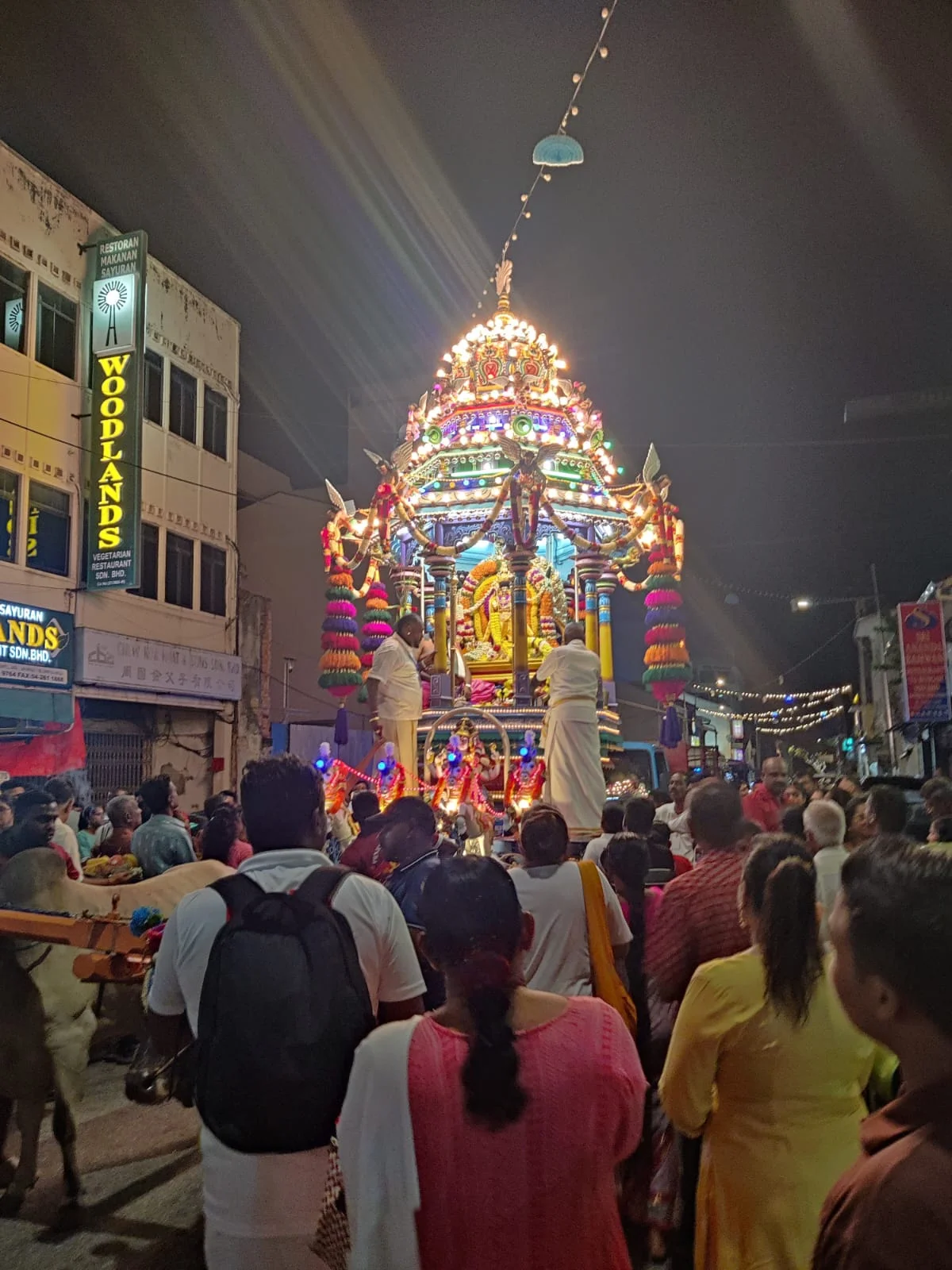 Grand night procession of the sacred Rath chariot passing Woodlands restaurant in Little India, Penang with crowds of devotees