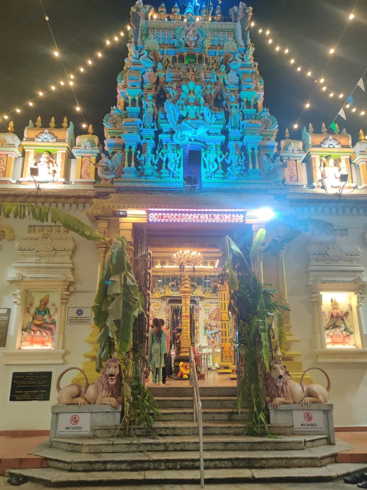 Arulmigu Sri Mahamariamman Temple entrance gopuram illuminated at night with guardian lions and the Rath procession announcement