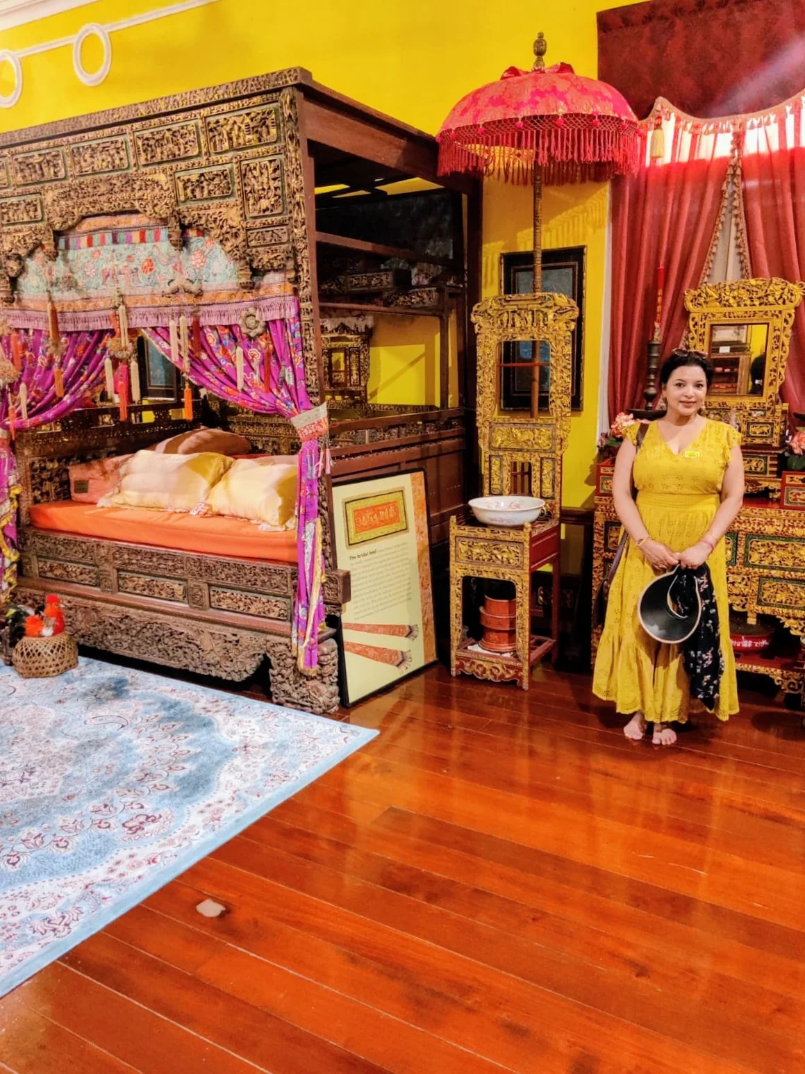Female traveler admiring the antique carved bridal bed and ceremonial silk draperies in the Chinese heritage home
