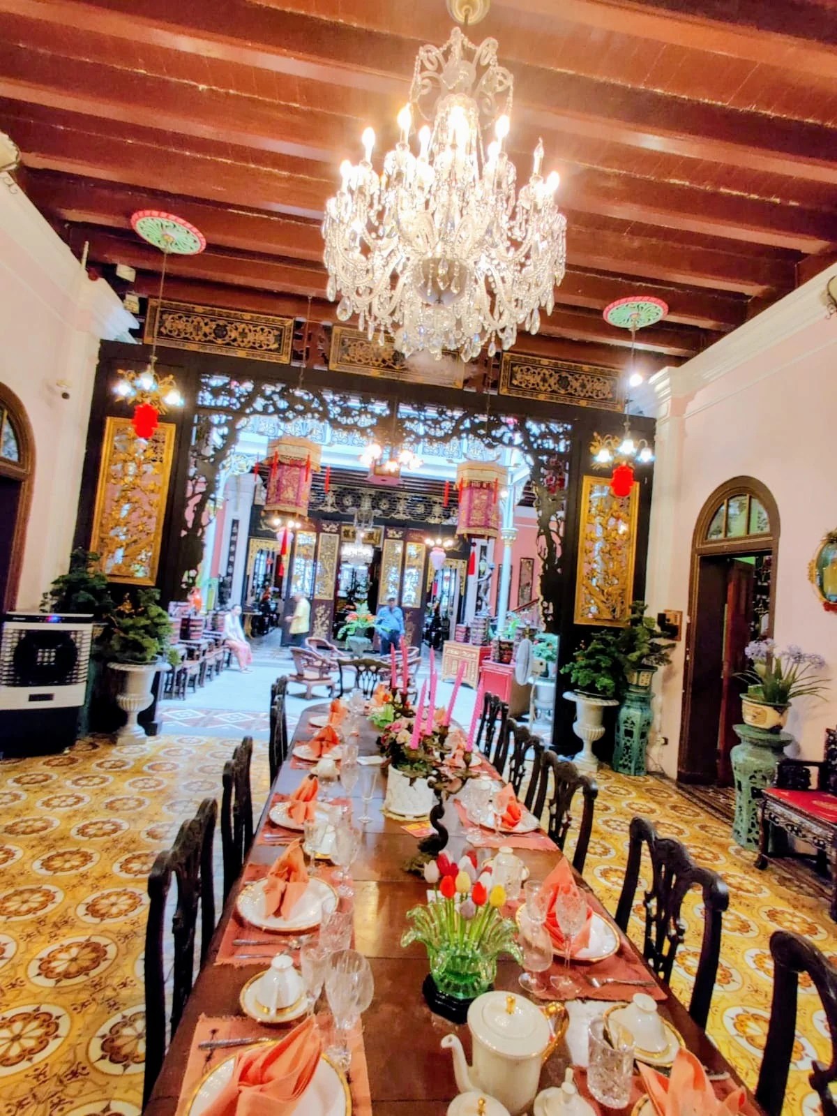 Grand dining hall of the Chinese heritage home with banquet table set with fine bone china and antique European glassware