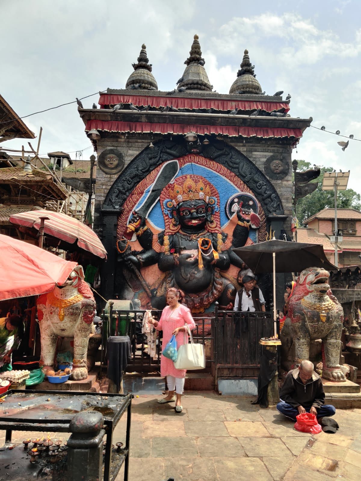 Colossal stone relief of Kala Bhairav in Kathmandu Durbar Square with stone lions and devotees