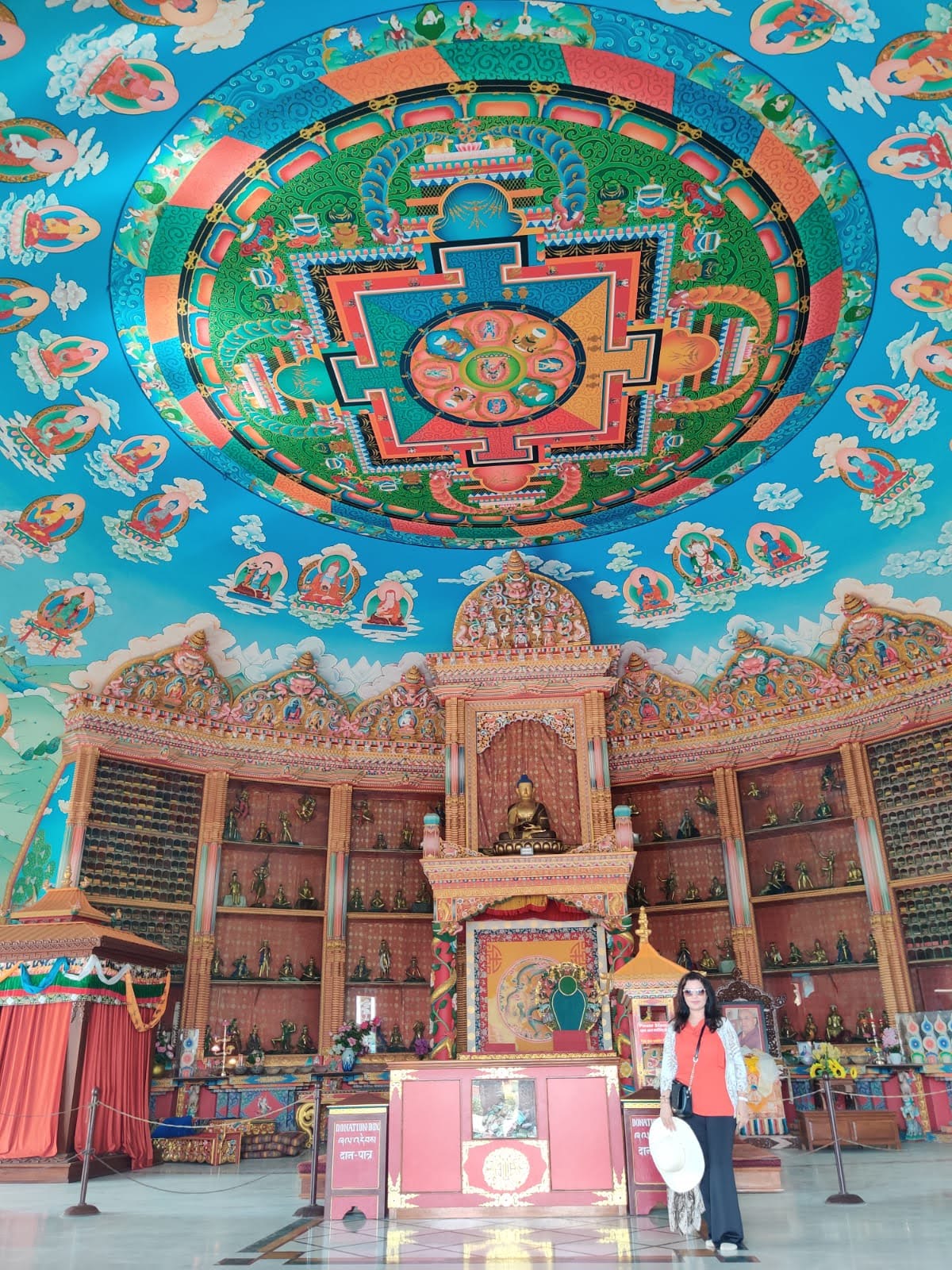 Traveler standing beneath the spectacular domed ceiling mandala and thousands of miniature Buddha statues inside the German Monastery