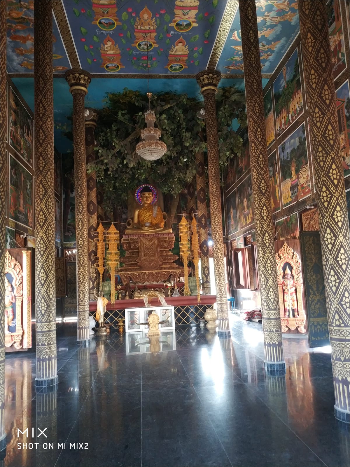 Interior prayer hall of the Royal Thai Monastery with golden Buddha statue and Thai lacquer columns