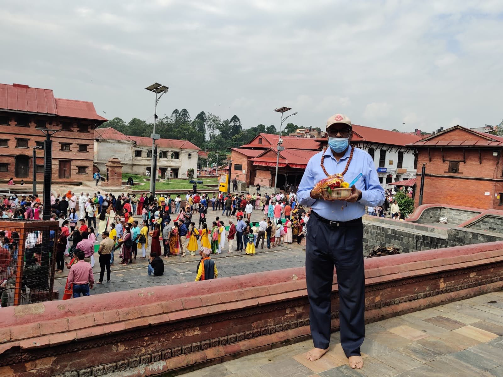 Devotee holding puja basket looking over the courtyard queue of hundreds of pilgrims at Pashupatinath