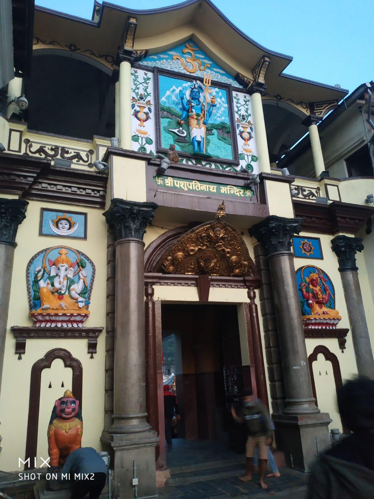 The ornate Western entrance portal of Pashupatinath Temple with gilded torana, Shiva mural, and guardian deities