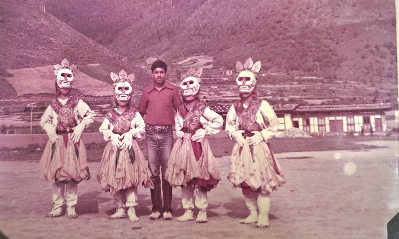 Traveler standing alongside Bhutanese Cham masked dancers wearing sacred Citipati skeleton skull masks