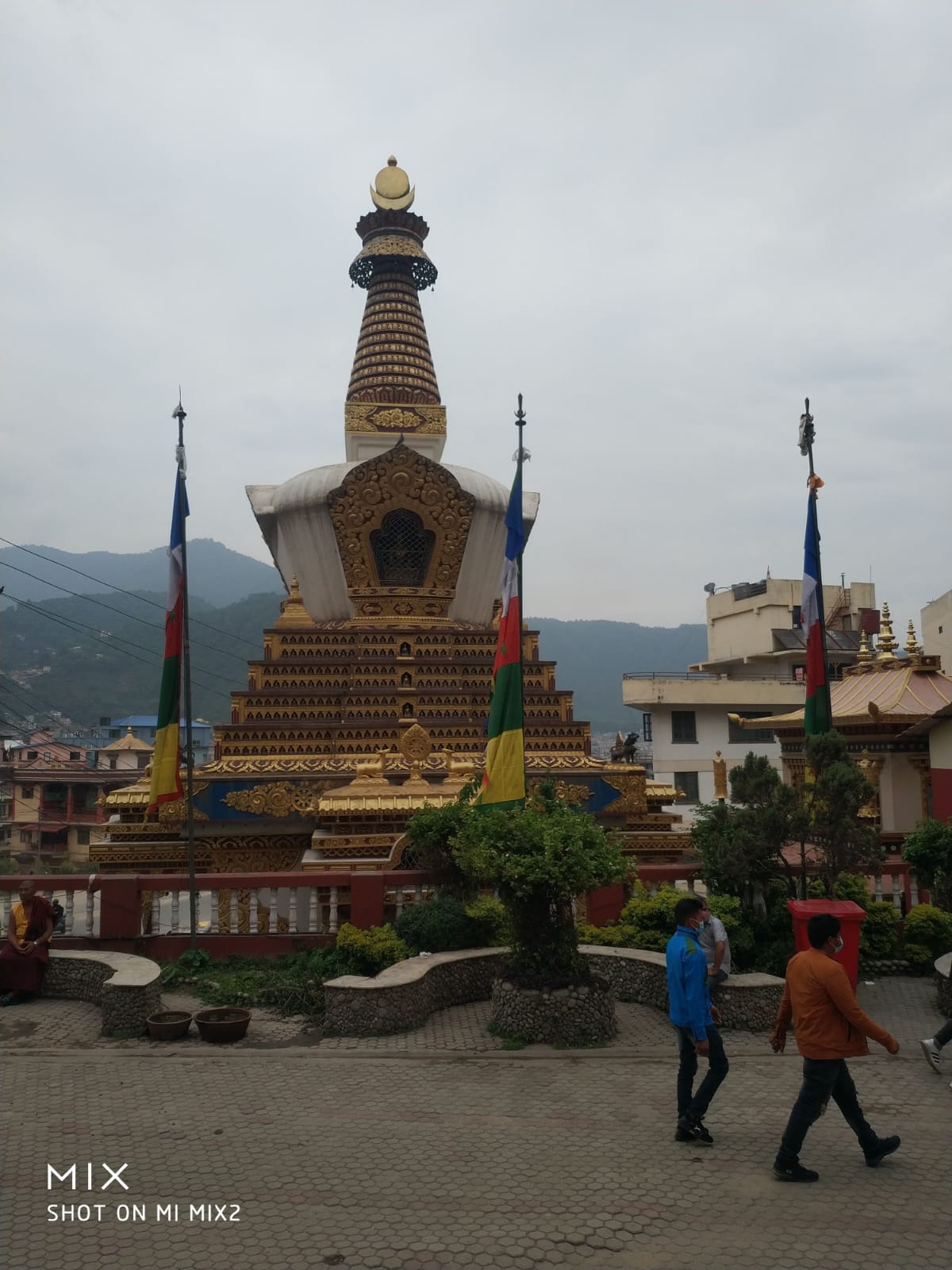 Tibetan chörten stupa crowned with golden spire and wind-blown prayer flags against Himalayan foothills