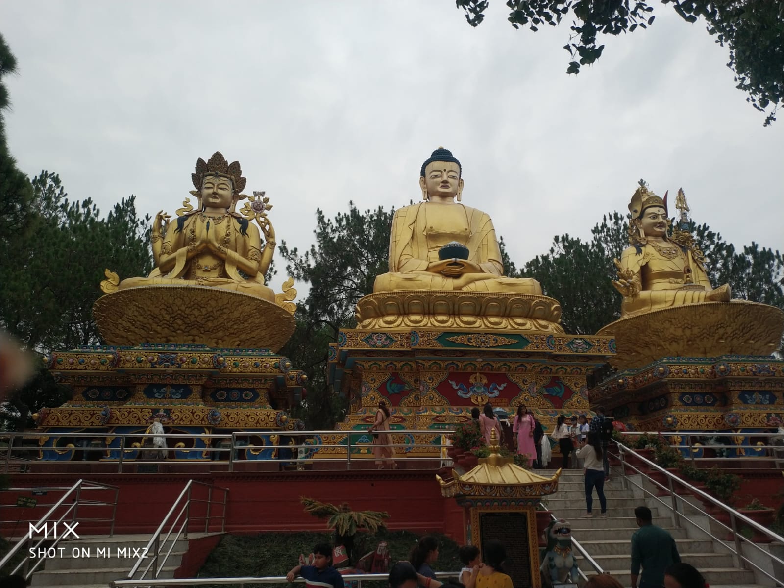 Panoramic view of the monumental golden Buddhist triad rising above the Kathmandu pine forests