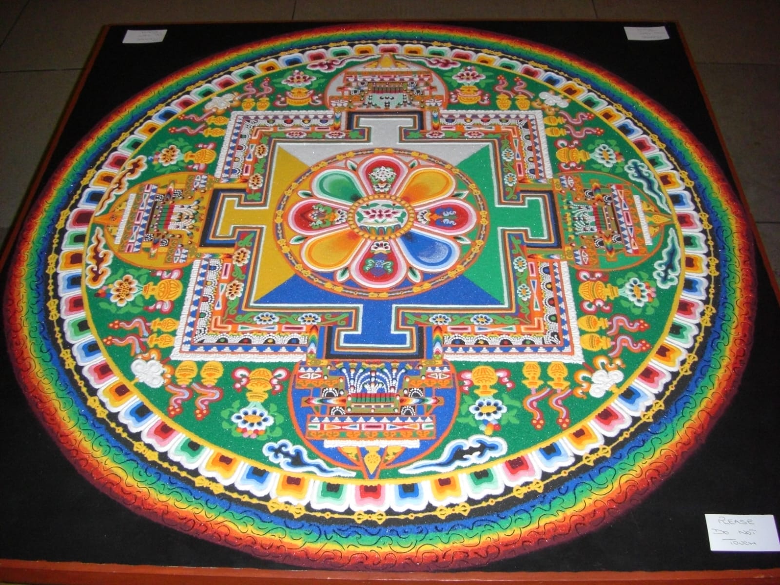 Meticulously crafted Tibetan sand mandala with concentric lotus gates and geometric cosmic palace