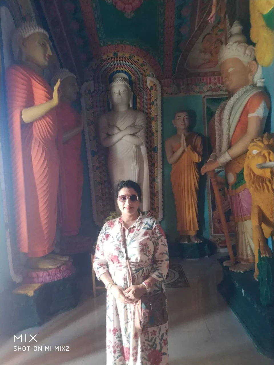 Shrine with standing Buddha statue flanked by disciples and guardian devas in Dambulla