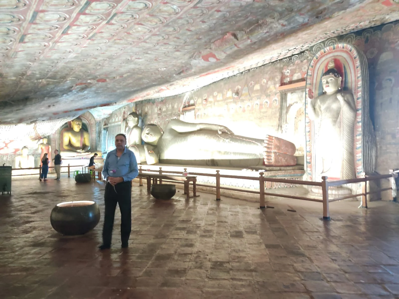 Devotee offering lotus flower before reclining and standing Buddhas in Dambulla Cave