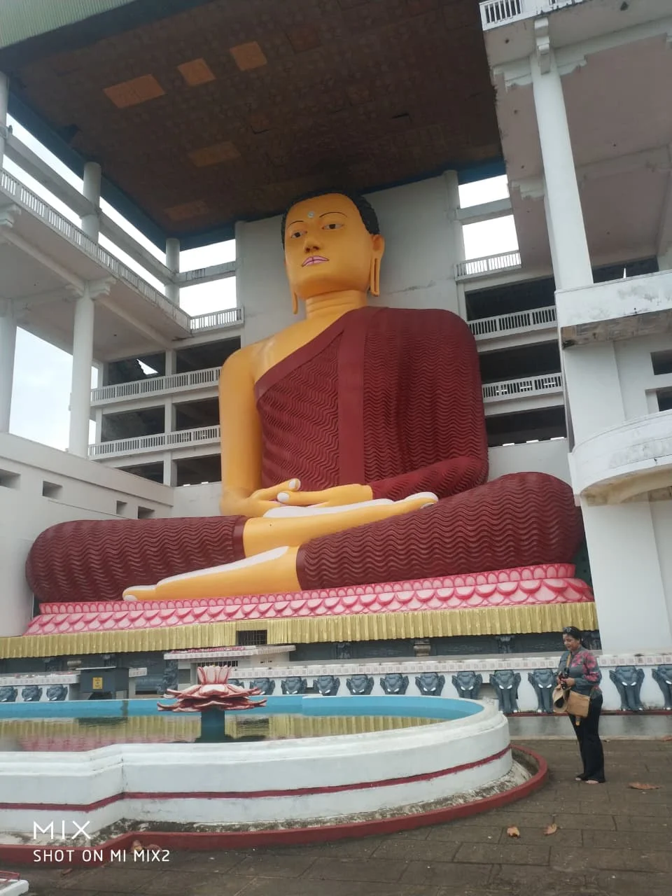 Courtyard enclosure framing the monumental seated Buddha statue in Weherahena