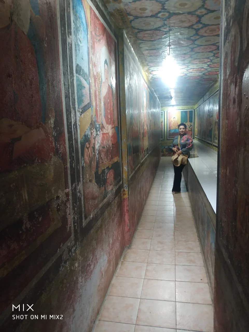 Pilgrim walking through the underground labyrinth of painted Buddhist narrative corridors