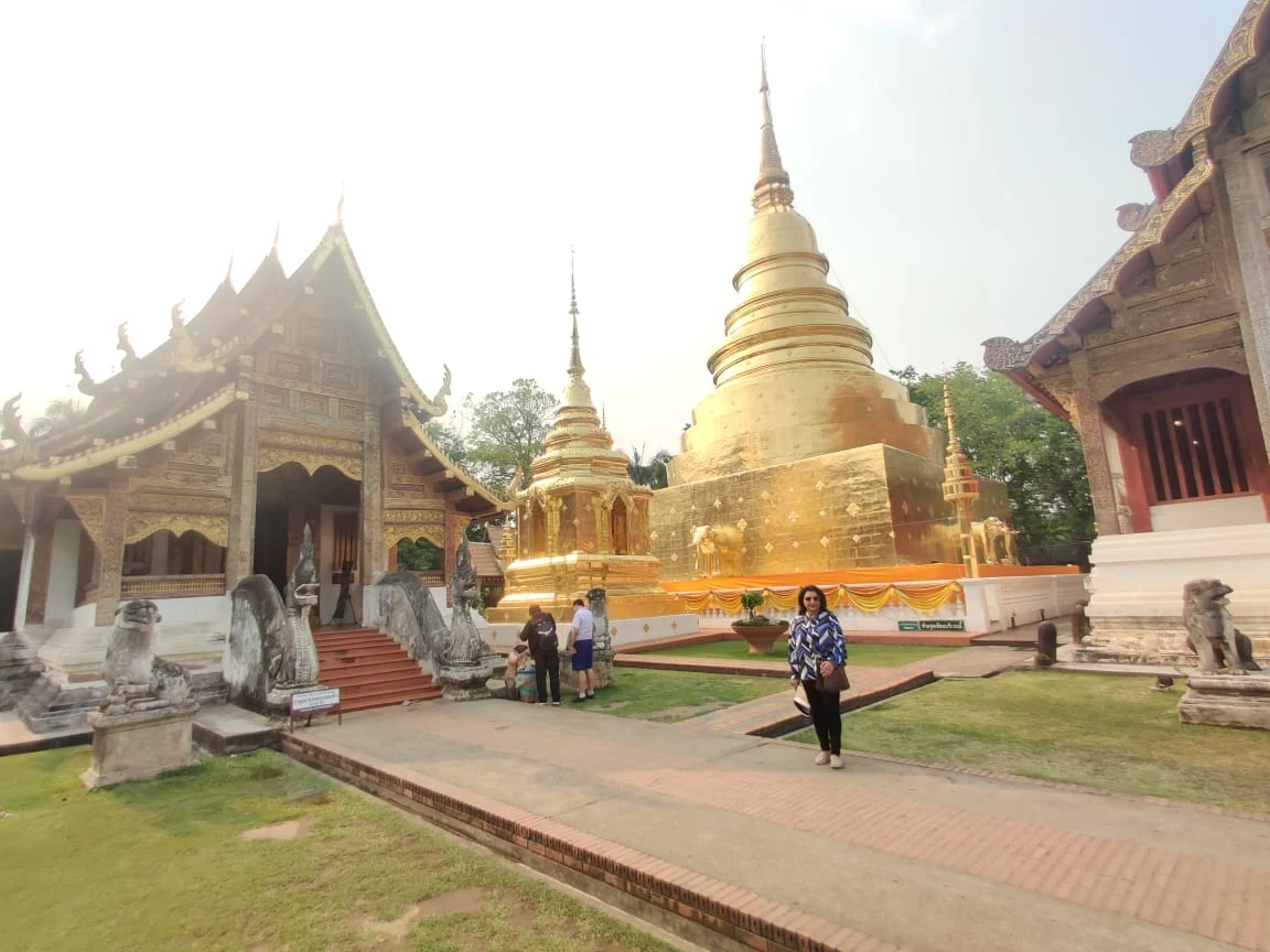 Wanderer in the sunlit courtyard of Wat Phra Singh with the golden chedi in the background