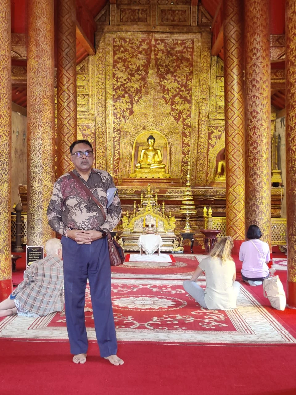 Wanderer standing inside Viharn Lai Kham before the Phra Phuttha Sihing Lion Buddha statue
