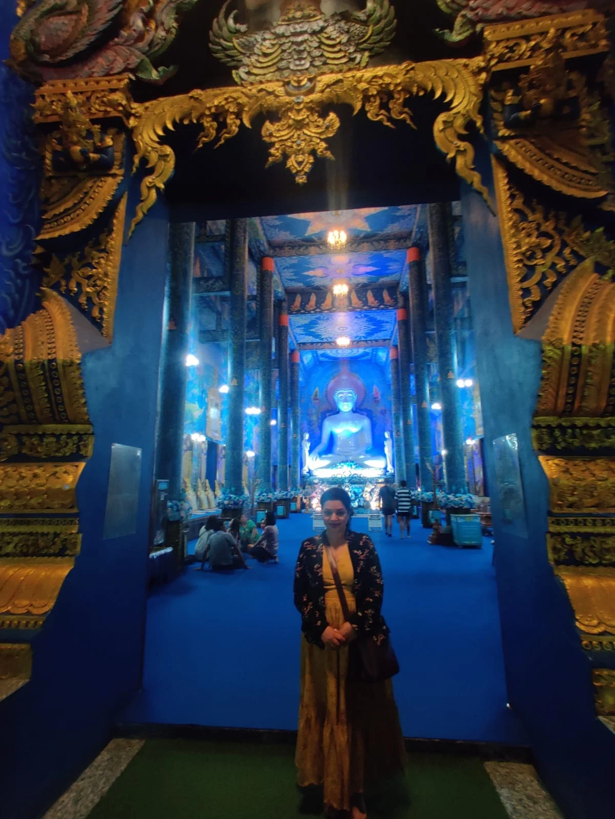 Wanderer at the radiant blue and gold threshold of Wat Rong Suea Ten