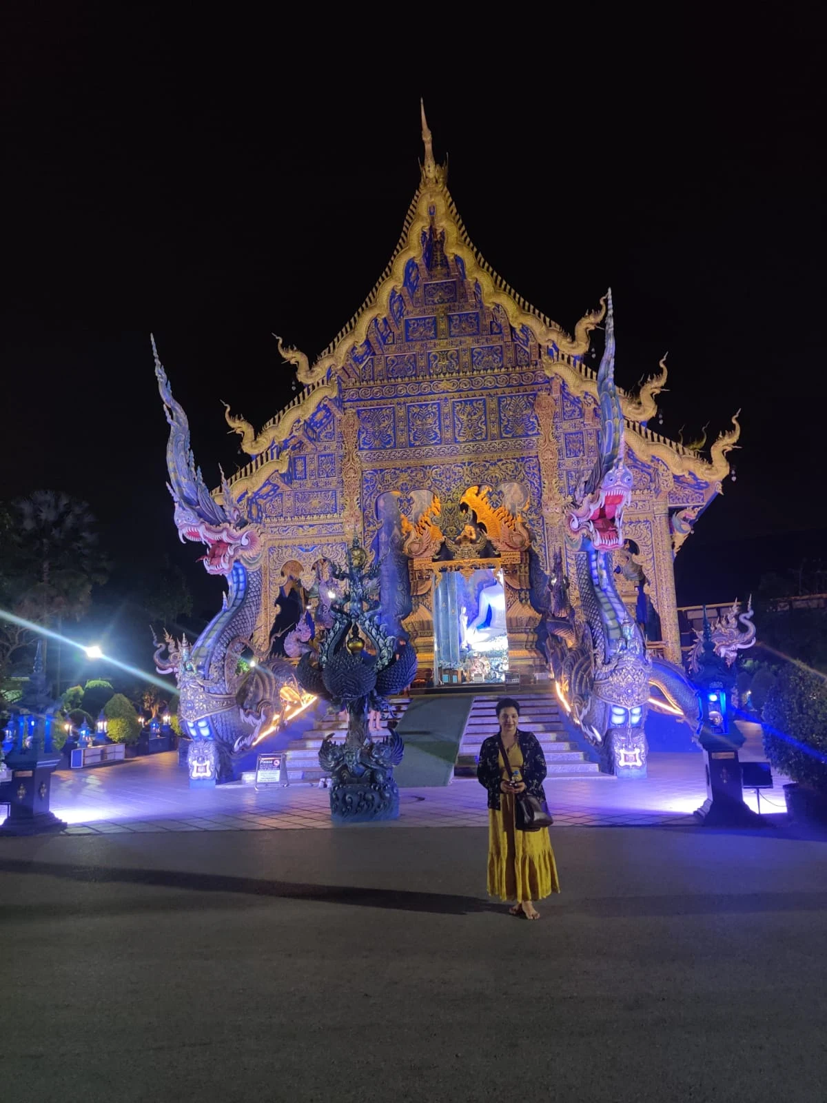 The dramatic illuminated cobalt blue and gold facade of Wat Rong Suea Ten at dusk