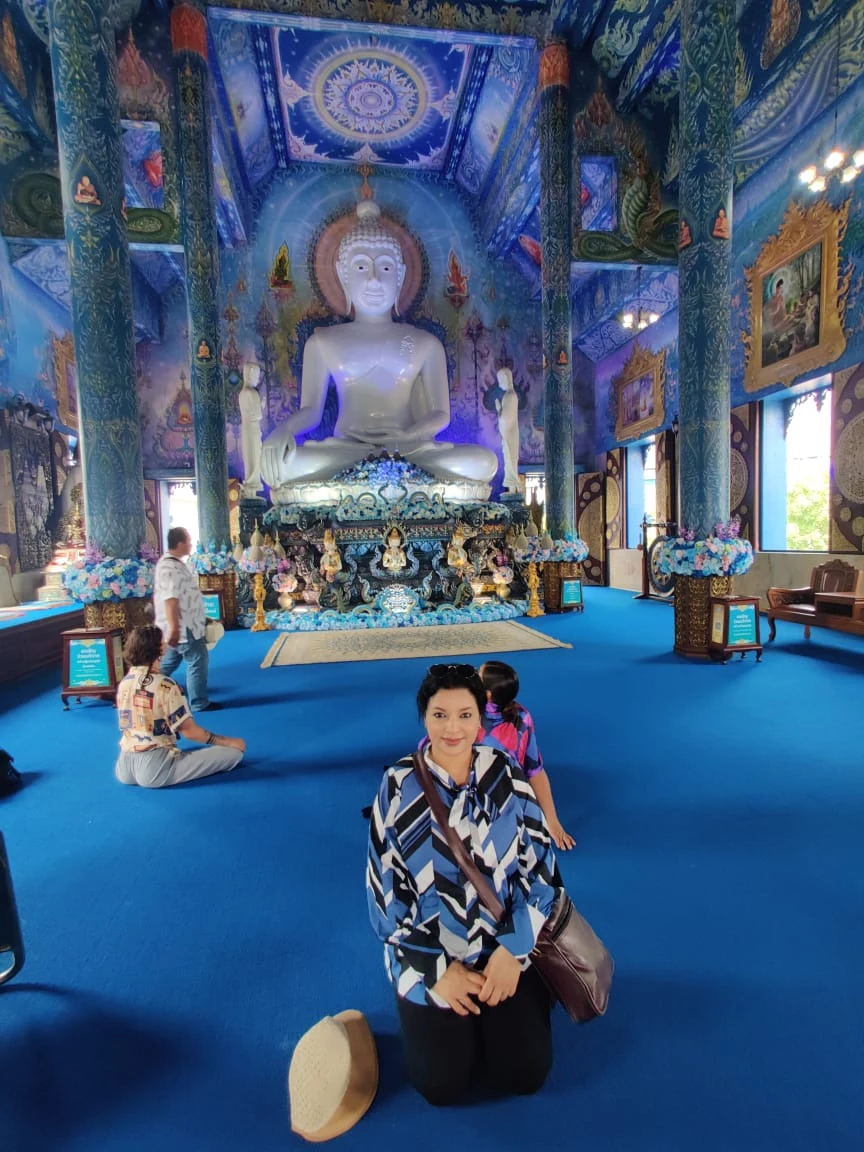 Wanderer inside the luminous blue sanctum of the Blue Temple before the white Buddha