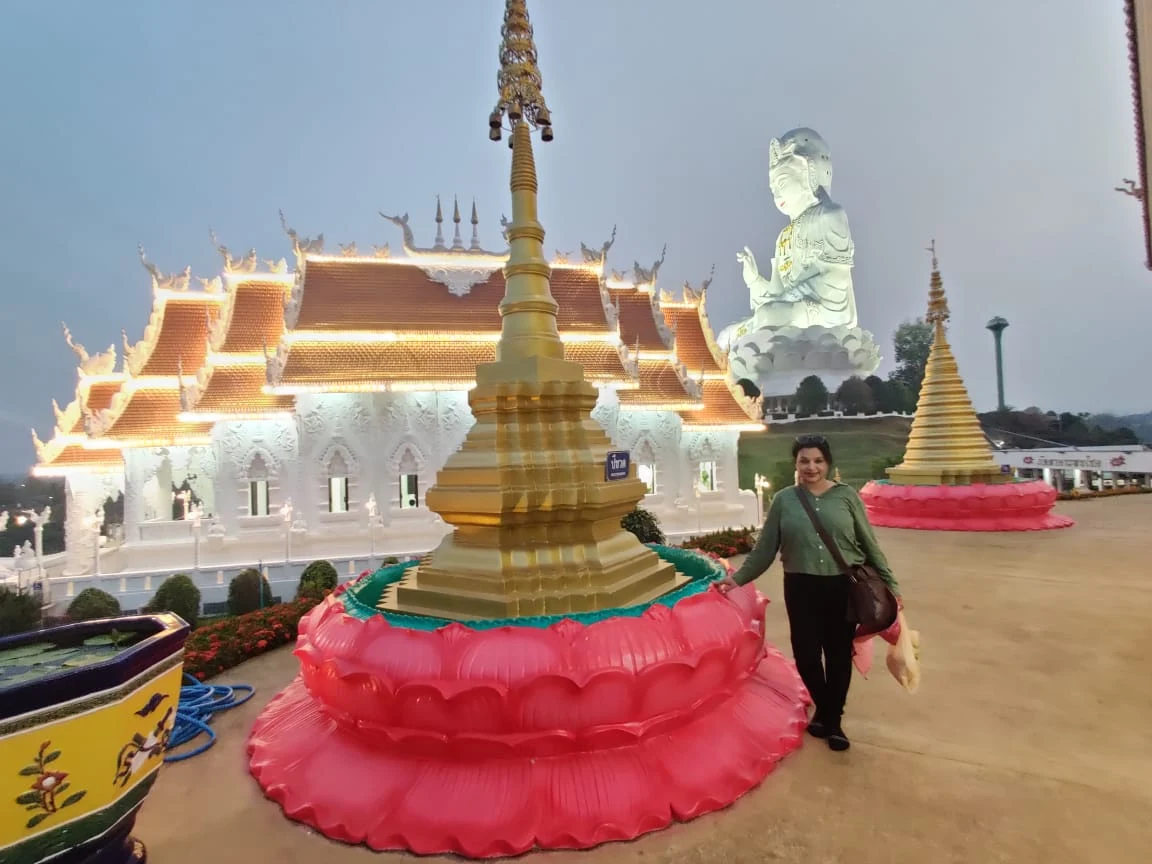 Colossal white Guan Yin statue overlooking the Chiang Rai countryside with traveler in foreground