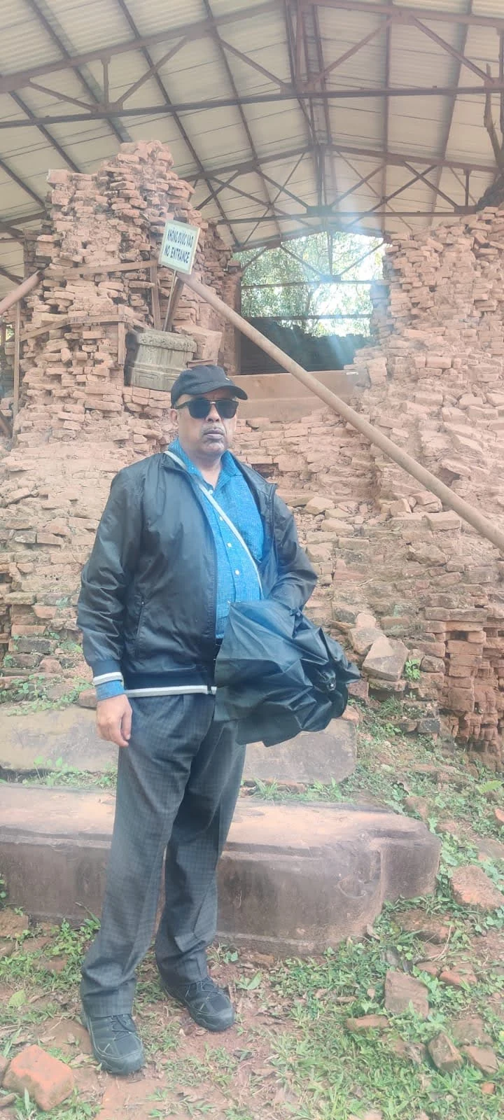 Traveler in front of sheltered brick temple ruins at My Son