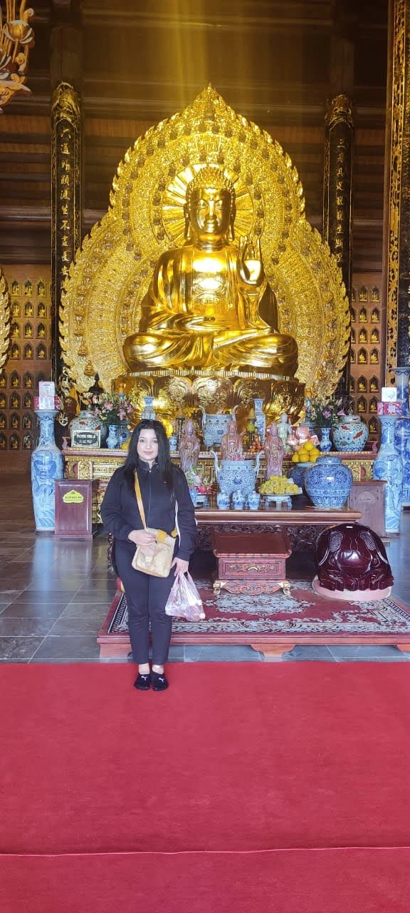 Female traveler standing before the radiant seated Golden Shakyamuni Buddha at Bai Dinh Pagoda