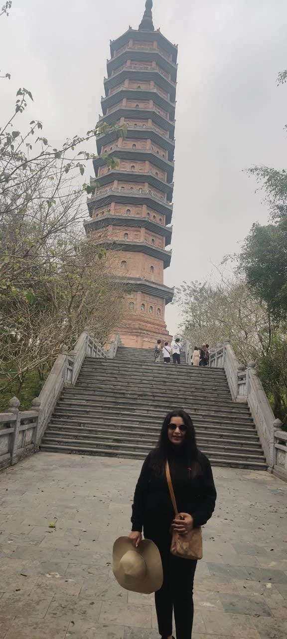 Traveler on the grand stone staircase leading up to the soaring thirteen-tier stupa tower at Bai Dinh Pagoda