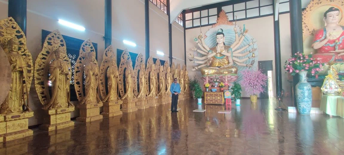 Male traveler in the hall of golden bodhisattvas and Avalokiteshvara at Linh An Pagoda in Da Lat