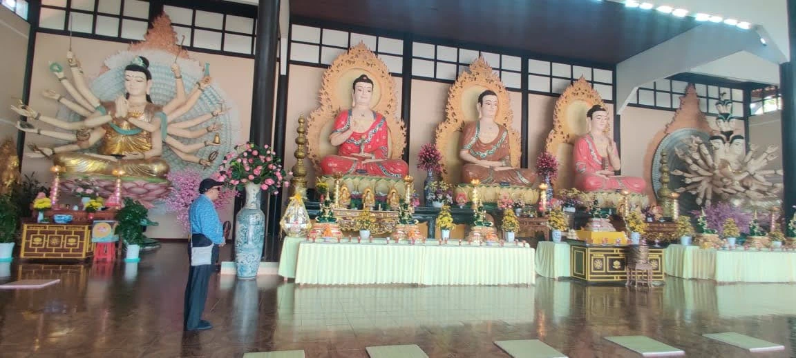 Inside Linh An Pagoda main sanctuary in Da Lat with three colossal seated Buddhas and multi-armed Avalokiteshvara