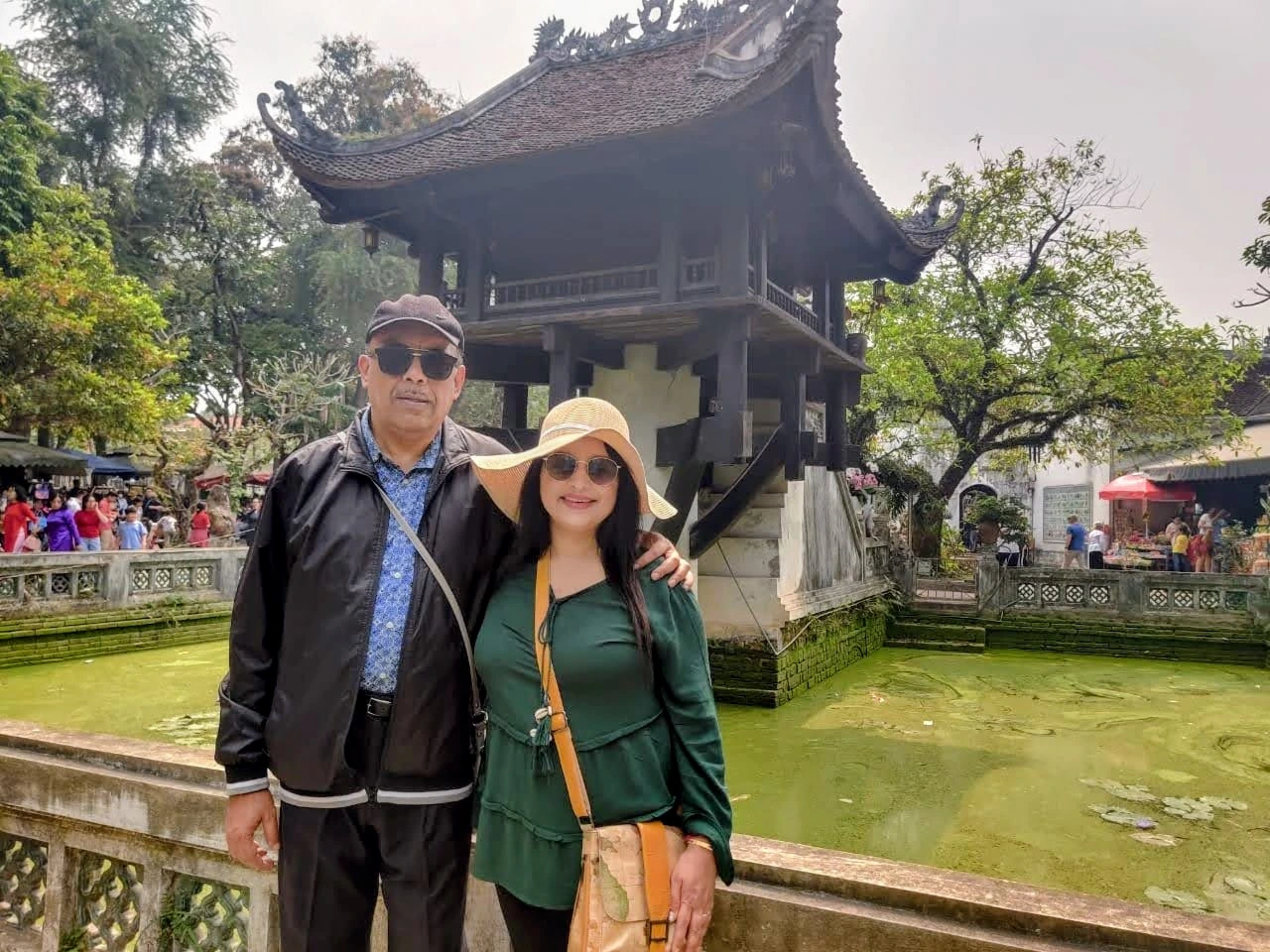 Couple portrait of Wanderers at 50 in front of the historic One Pillar Pagoda in Hanoi across the lotus pond