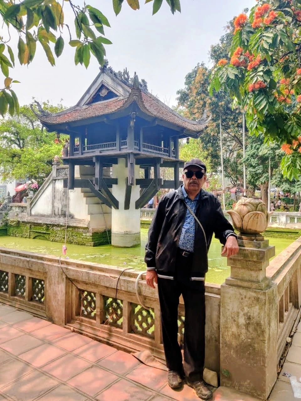 Male traveler beside the lotus pond and carved stone lotus blossom balustrade at the One Pillar Pagoda