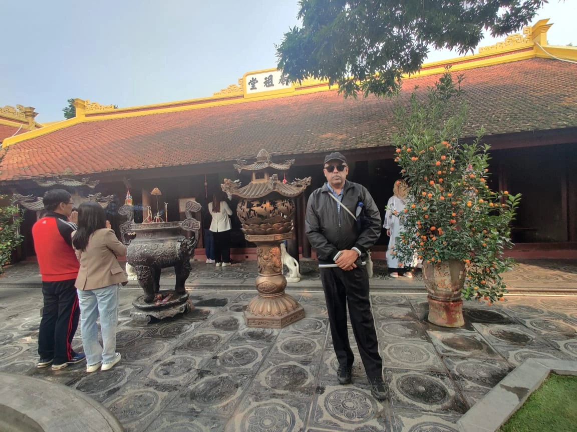 Male traveler in the courtyard of Tran Quoc Pagoda in Hanoi before the ancestral hall and bronze incense burner