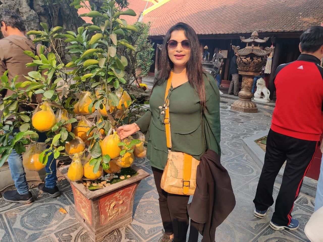 Female traveler in the peaceful courtyard of Tran Quoc Pagoda in Hanoi beside an auspicious pomelo bonsai tree