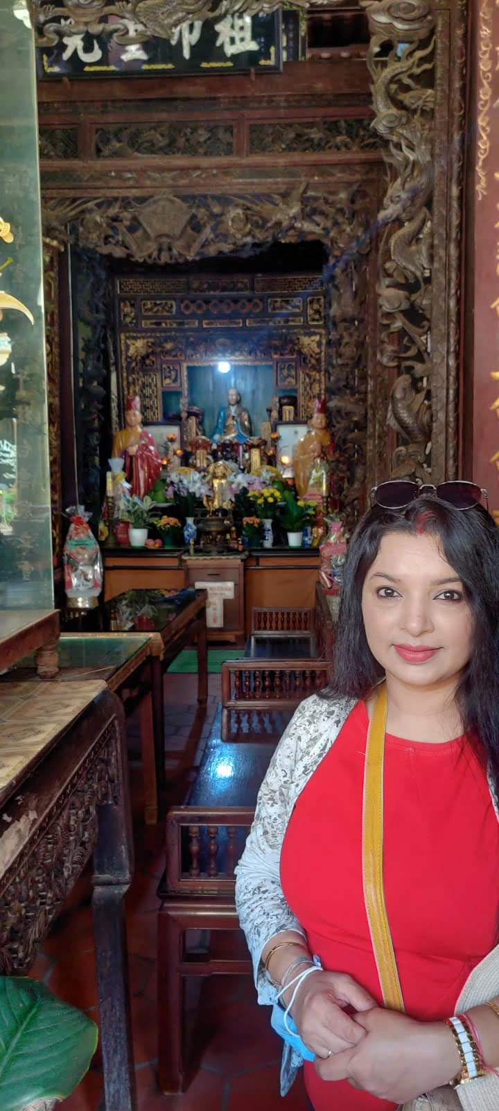 Female traveler in the ornate wooden hall of Vinh Trang Pagoda before ancestral Buddhist shrines