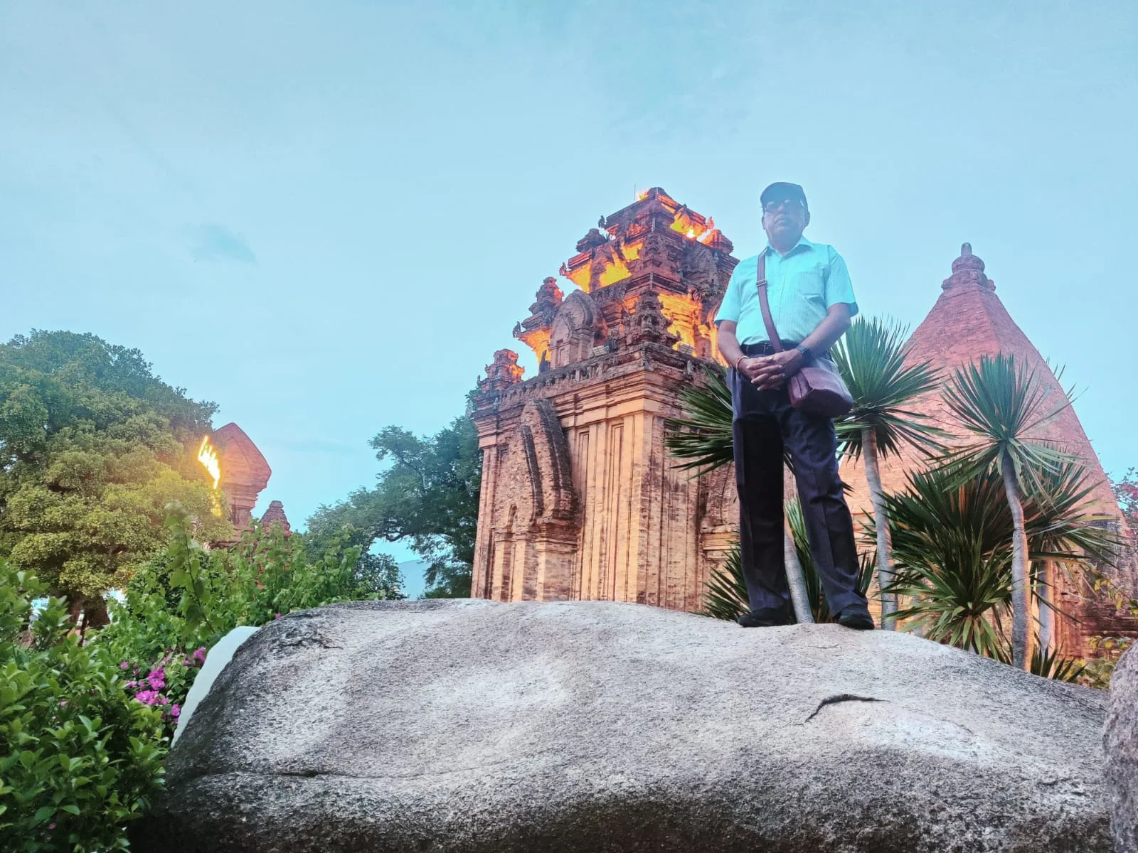 Traveler sitting upon granite boulder contemplating the Po Nagar sanctuary at twilight