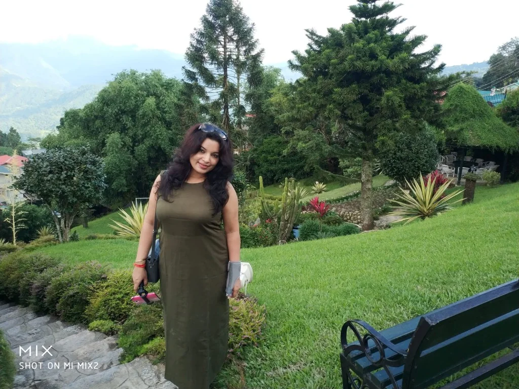 A woman standing in a lush manicured garden
