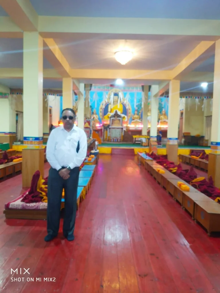 Polished wooden floor prayer hall and golden Buddha shrine inside Bomdila Monastery