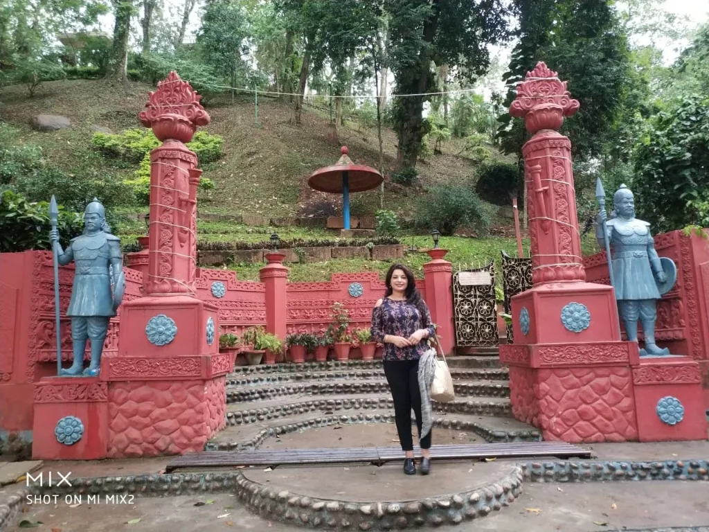 Ornate red heritage gate pillars and warrior sculptures at Cole Park
