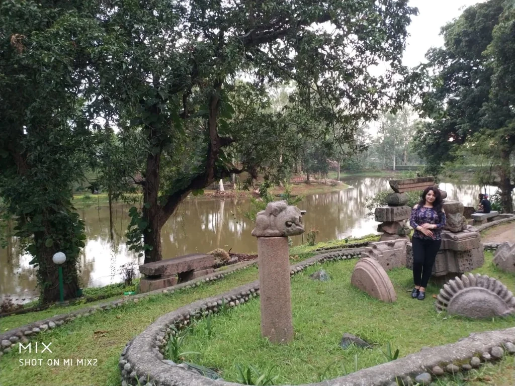 Ancient stone archaeological sculptures amidst lush gardens by the lake