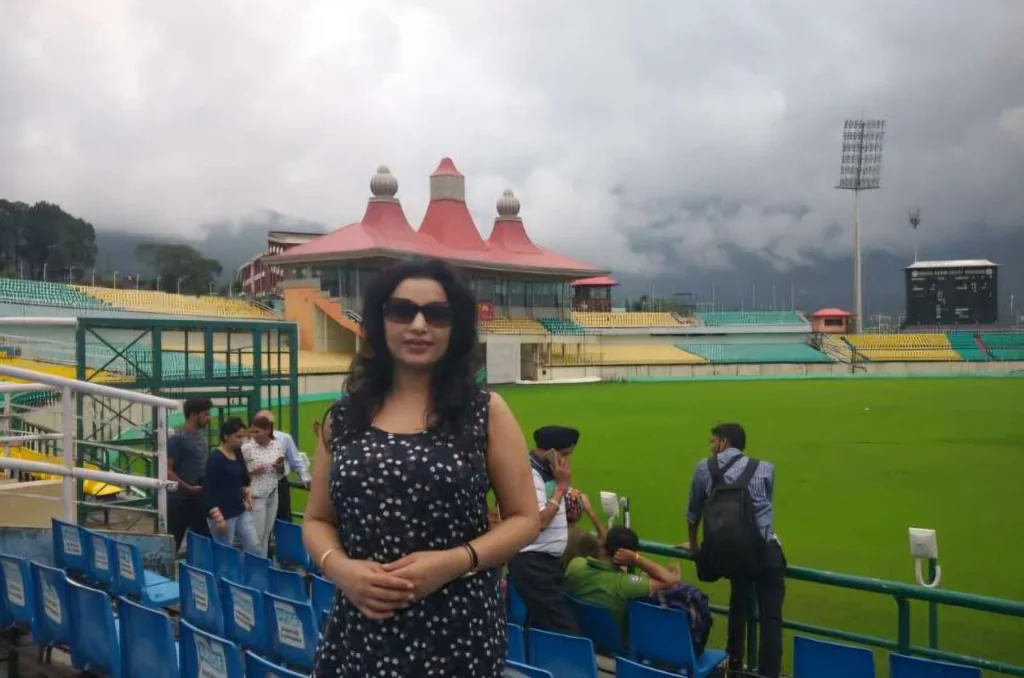Traveler standing in front of the HPCA Stadium in Dharamshala under a cloudy sky