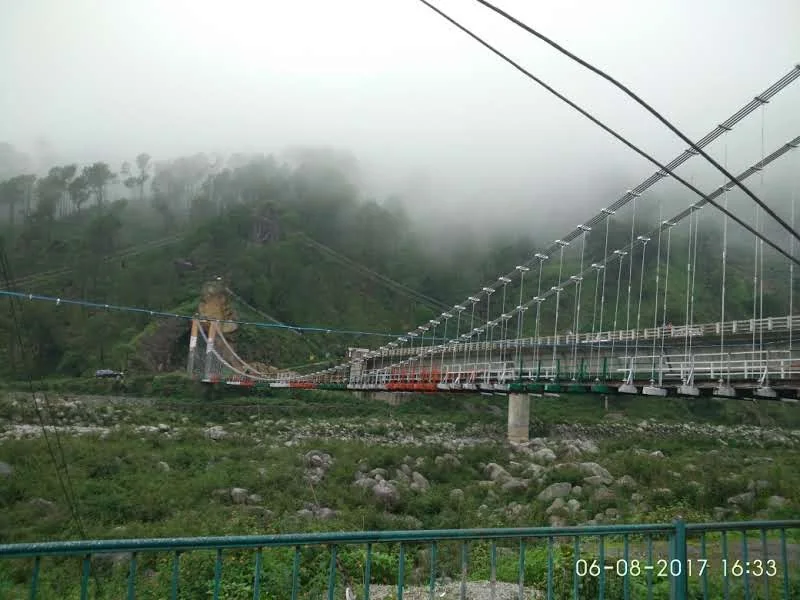 Neugal Khad suspension bridge under low mist and cloudy skies in Palampur