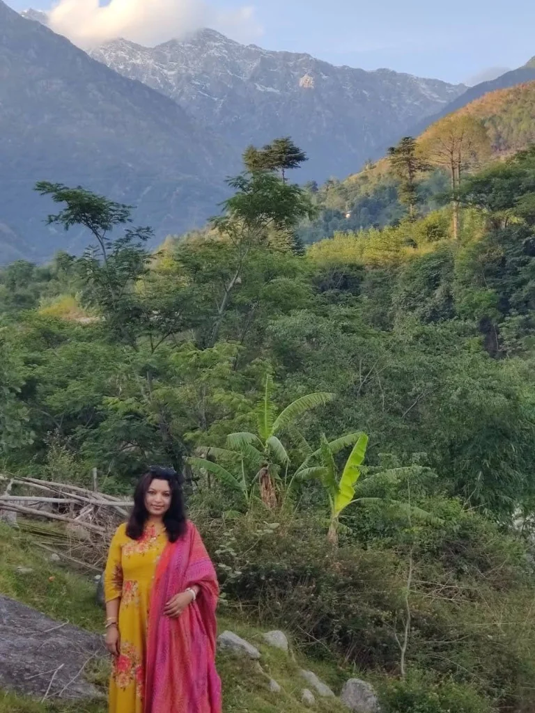 A traveler standing in front of lush green valley slopes and towering pine forests in Palampur