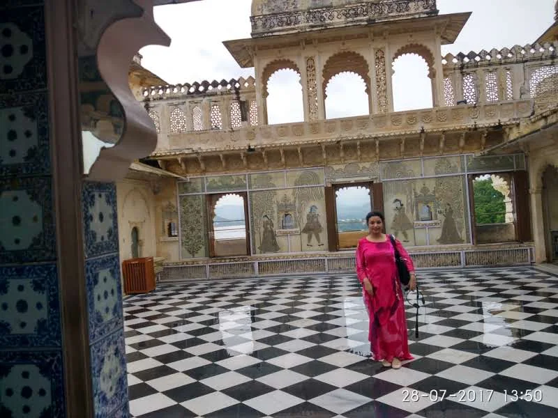 Open marble terrace with checkered floor, blue ceramic tiles, and historic mural paintings at Badi Mahal