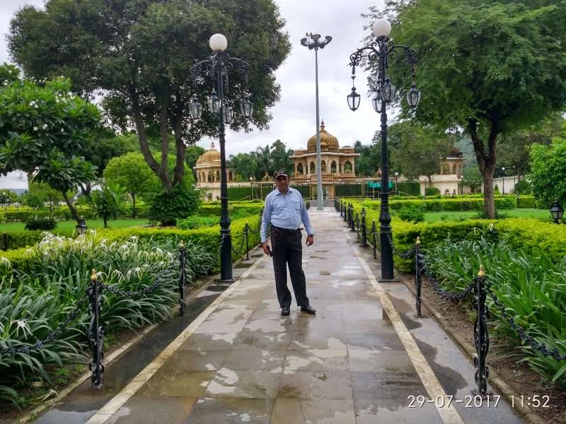 Paved garden walkway path lined with classic lamp posts and manicured hedges leading towards Jag Mandir pavilions